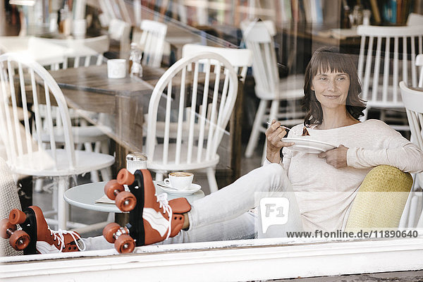 Frau mit Rollschuhen in einem Café sitzend  Kuchen essend