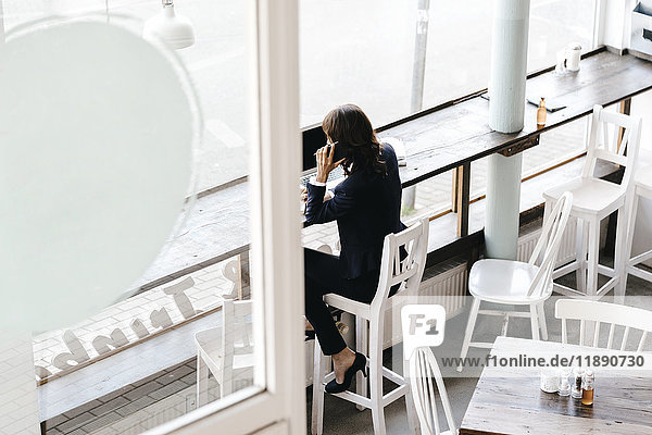 Geschäftsfrau im Café  mit Smartphone und Laptop