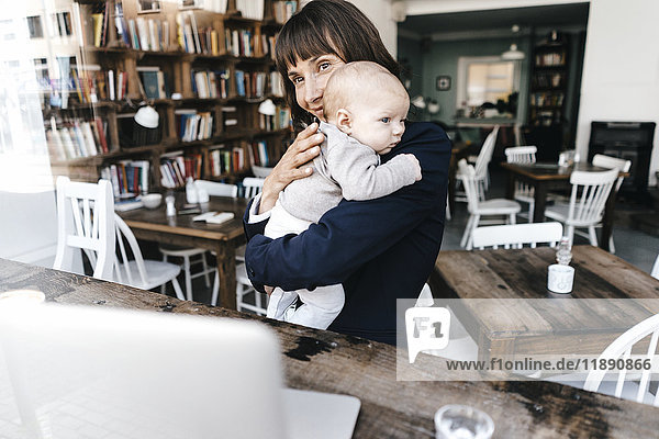 Businesswoman in cafe holding baby
