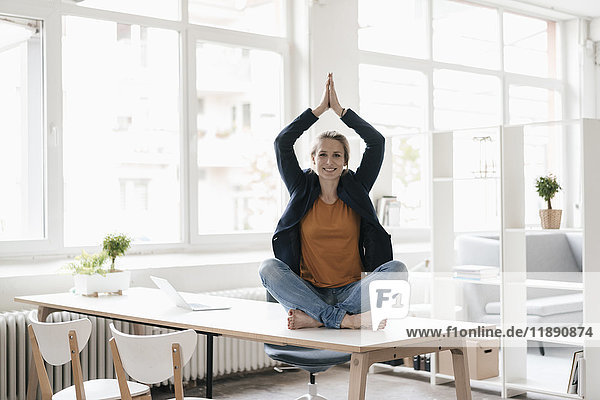 Geschäftsfrau beim Yoga auf dem Schreibtisch im Loft