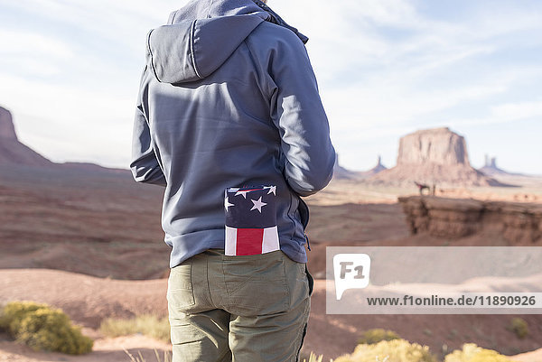 USA  Utah  Rückansicht des jungen Mannes mit gefalteter amerikanischer Flagge in der Tasche im Monument Valley