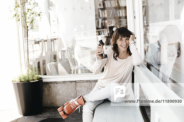Frau mit Rollschuhen in einem Café sitzend  Bier trinkend