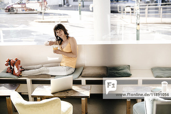 Frau mit Rollschuhen in einem Café sitzend  einen Drink nehmend