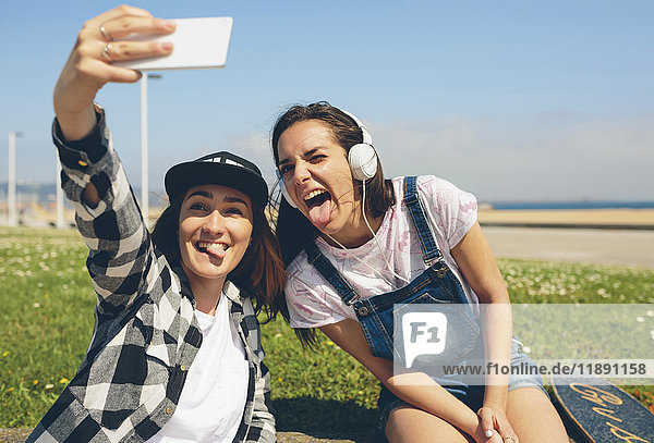Porträt von zwei jungen Frauen  die sich selbst mit dem Smartphone fotografieren.