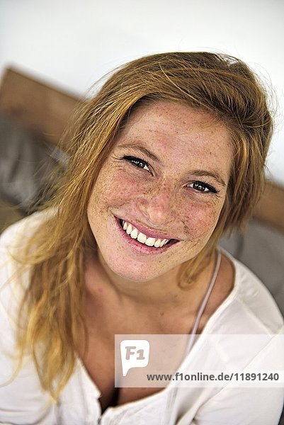 Porträt der lachenden erdbeerblonden jungen Frau mit Sommersprossen