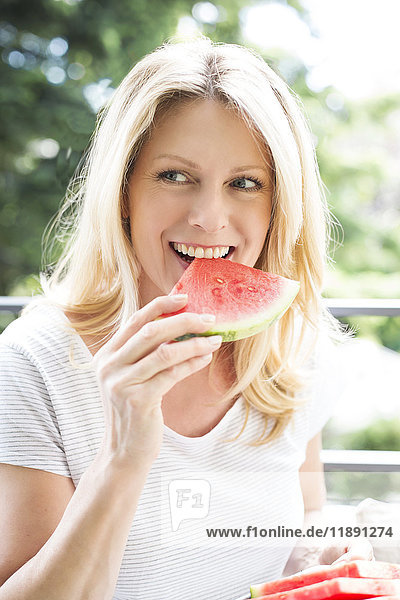 Mature woman sitting on balcony  eating water melon  portrait