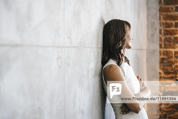 Businesswoman leaning against wall with arms crossed