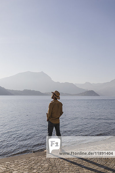 Italy  Lierna  man standing at lakeside promenade enjoying sunset