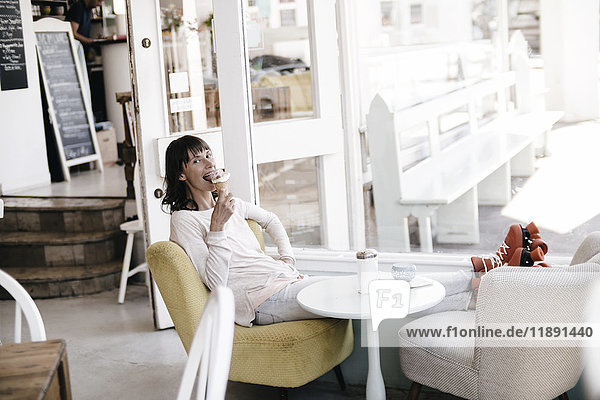 Frau mit Rollschuhen in einem Café sitzend  Eis essend