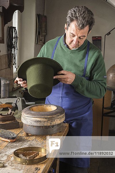 Hutmacher  der einen trockenen Wollfilzhut über eine Kantenform hält  Hutmacherwerkstatt  Bad Aussee  Steiermark  Österreich  Europa