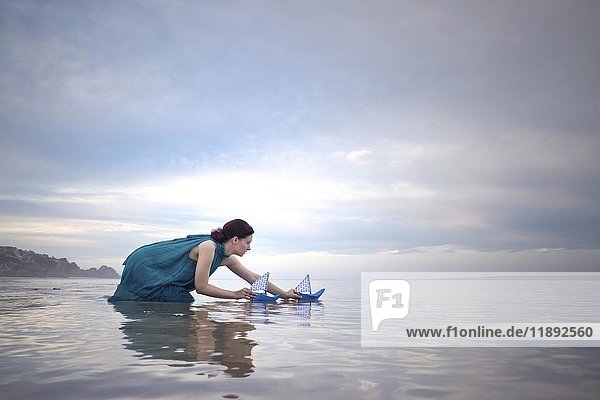 Frau mit blauen Papierschiffen bei Ebbe am Strand