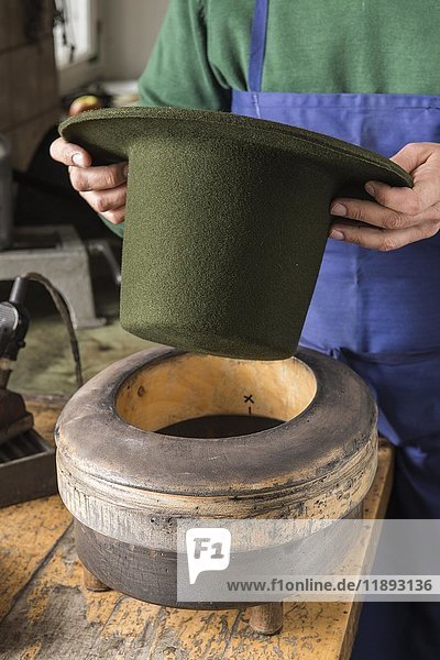 Hände halten einen trockenen Wollfilzhut über eine Randform  Hutmacherwerkstatt  Bad Aussee  Steiermark  Österreich  Europa