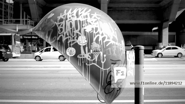 Verkehr und Mann, der durch ein mit Graffiti beschmiertes Münztelefon geht