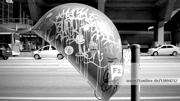 Verkehr und Mann  der durch ein mit Graffiti beschmiertes Münztelefon geht