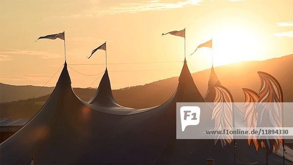 Musikfestival-Zelt mit wehenden Fahnen bei Sonnenuntergang