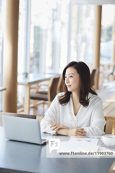 Japanische Frau mit Laptop in einem stilvollen Cafe