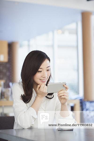 Japanese woman with smartphone in a stylish cafe