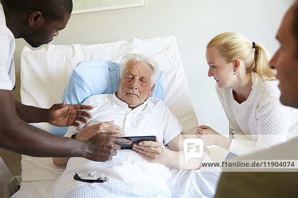 Krankenpfleger zeigt digitales Tablett für Senioren und Paare auf der Krankenstation