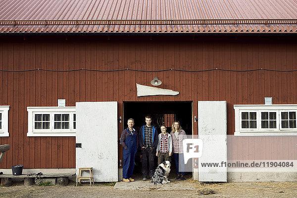 Bauer stehend mit Familie am Eingang der Scheune