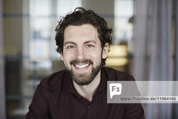 Portrait of smiling businessman standing at creative office