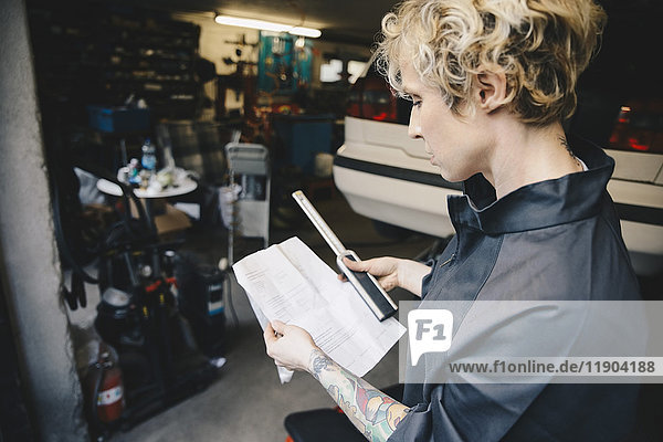 Side view of female mechanic reading checklist at auto repair shop