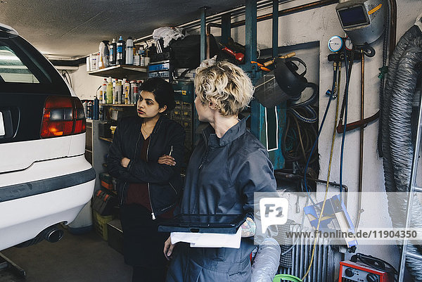Mechanikerin mit Kundin bei der Kfz-Werkstatt