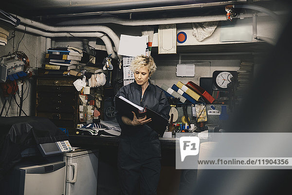 Female mechanic reading document in auto repair shop