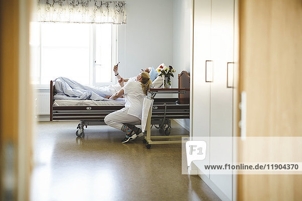 Krankenschwester und älterer Mann  der Selfie mit Smartphone in der Krankenstation nimmt