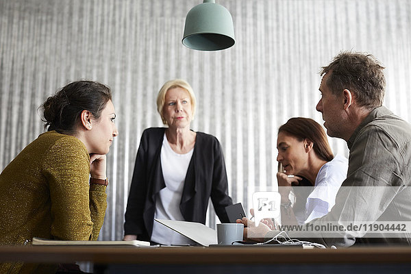 Businessman discussing with female colleagues in board room at creative office