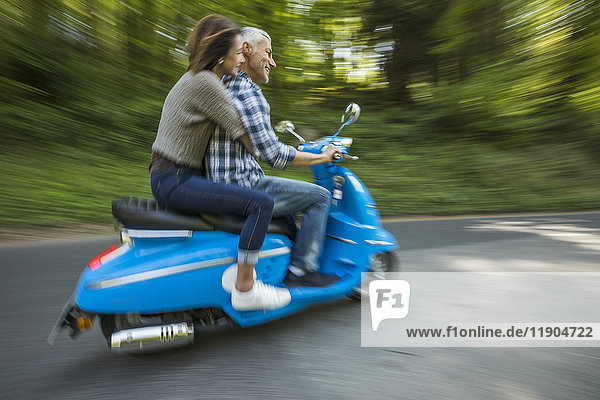 Kaukasisches Paar fährt blauen Motorroller