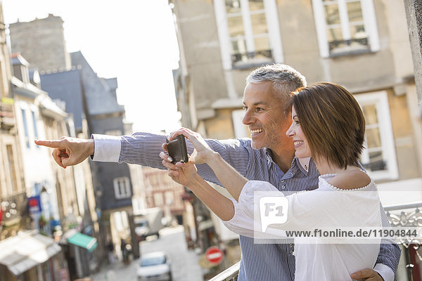 Caucasian couple photographing with cell phone in city