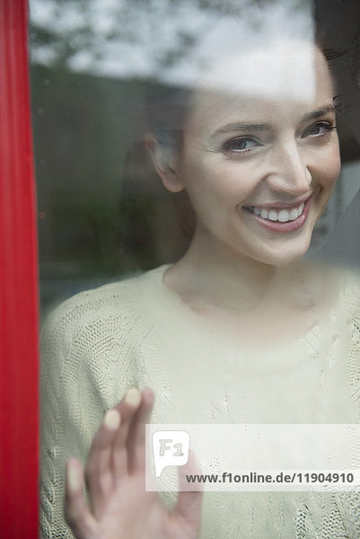 Kaukasische Frau lächelt hinter einem nebligen Fenster