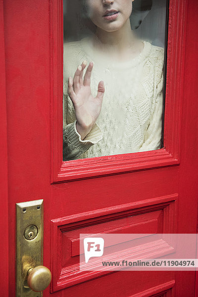 Kaukasische Frau träumt hinter roter Tür