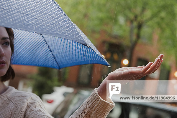 Kaukasische Frau hält Regenschirm bei Regen