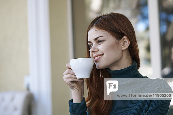Kaukasische Frau lächelt und trinkt Kaffee