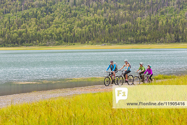 Ehepaar mit Sohn und Tochter fahren in der Nähe des Sees Fahrrad