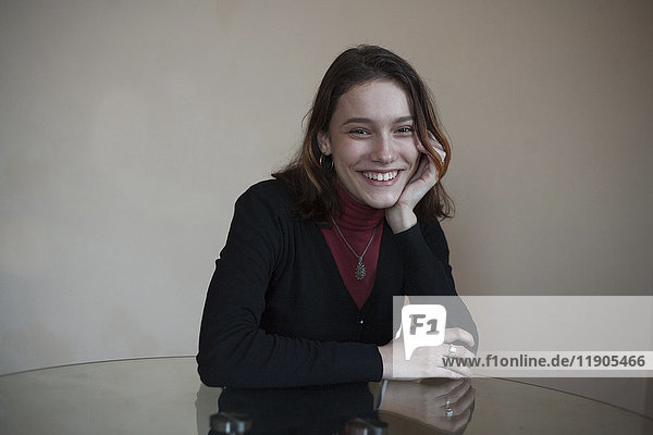 Porträt einer lächelnden kaukasischen Frau  die am Tisch sitzt