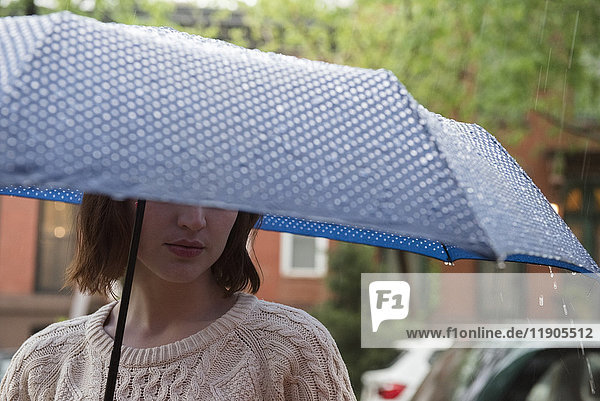 Kaukasische Frau hält einen Regenschirm im Regen