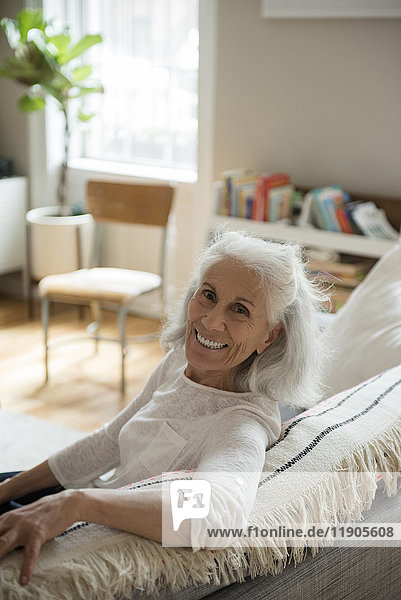 Porträt einer lächelnden älteren Frau auf dem Sofa