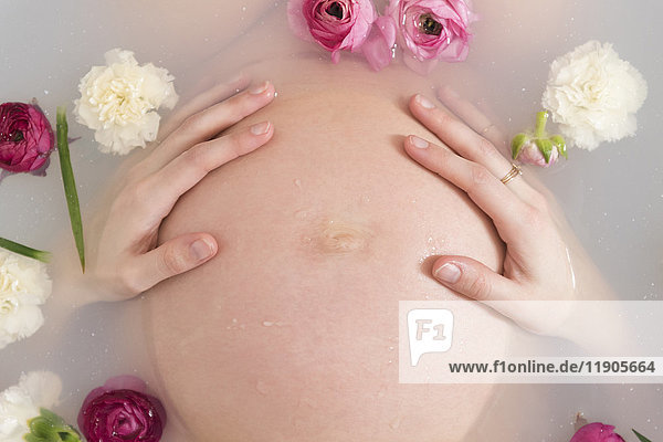 Kaukasische werdende Mutter im Milchbad mit Blumen