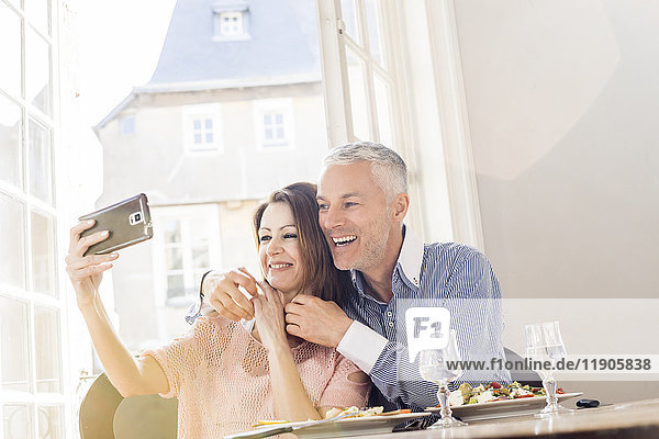 Kaukasisches Paar  das für ein Selfie mit dem Handy in einem Restaurant posiert