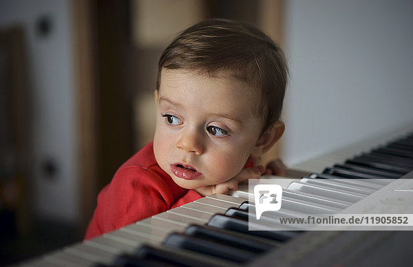 Neugieriger Junge lehnt am Klavier