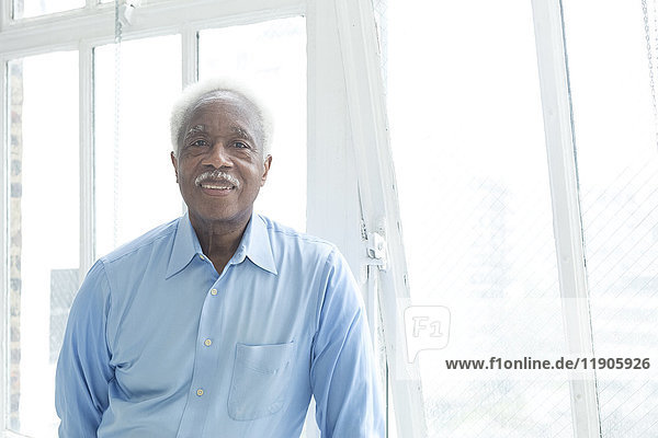 Lächelnder älterer schwarzer Mann in der Nähe des Fensters
