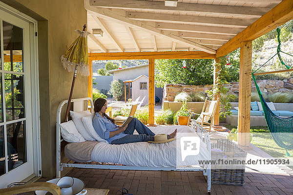 Ältere kaukasische Frau liest Bücher auf dem Bett auf der Terrasse