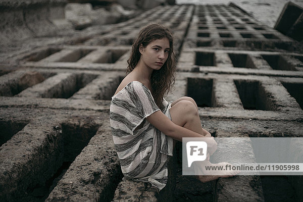 Porträt eines kaukasischen Teenagers  der auf einer Struktur sitzt
