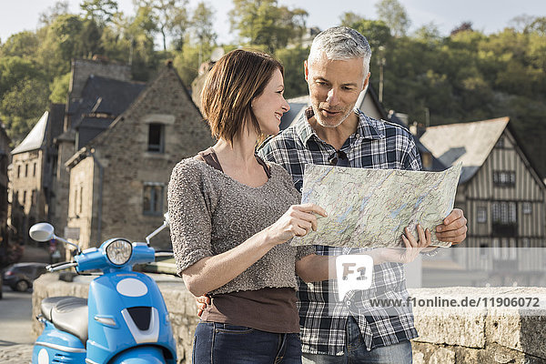 Kaukasisches Paar in der Nähe eines blauen Motorrollers  das eine Karte liest