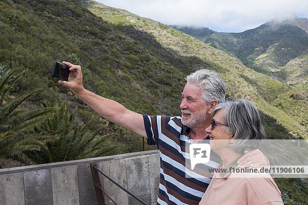 Ältere kaukasische Paare  die für ein Selfie mit dem Handy posieren