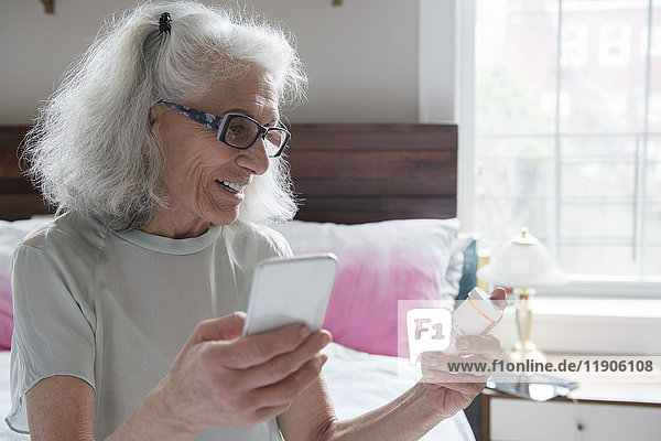 Ältere Frau prüft Rezept mit Mobiltelefon
