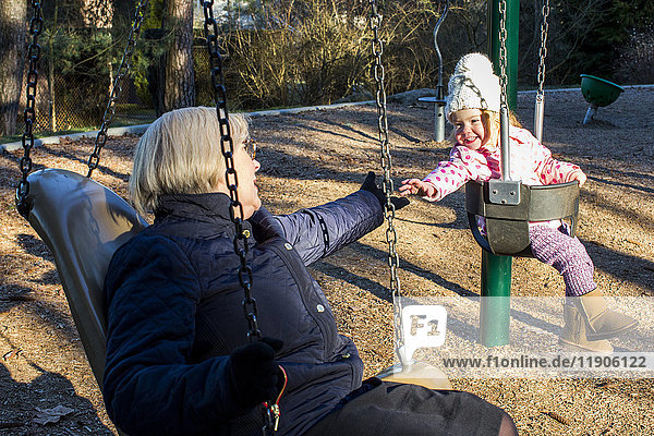 Caucasian grandmother and granddaughter on swings