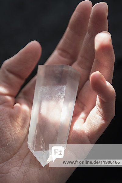 Hand einer kaukasischen Frau hält Kristall